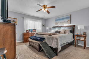 Primary Bedroom featuring light carpet, a textured ceiling, and ceiling fan