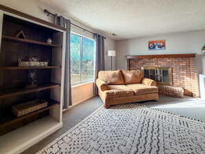 Carpeted living room featuring a textured ceiling and a brick fireplace