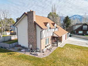 Rear view of property with brick siding, roof with shingles, a chimney, driveway, and a garage