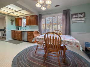 Dining area with a wainscoted wall, light colored carpet, a decorative wall, and a chandelier