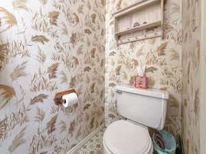 Bathroom with wallpapered walls and tile patterned floors