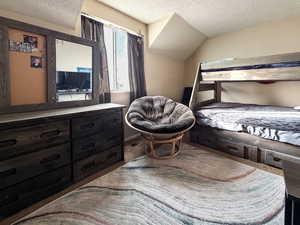 Bedroom with a textured ceiling and vaulted ceiling