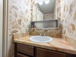 Bathroom with wallpapered walls and vanity