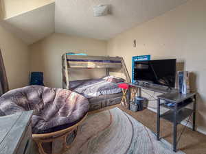 Bedroom with carpet flooring, a textured ceiling, and vaulted ceiling