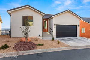 View of front of home featuring a tiled roof, an attached garage, driveway, and stucco siding