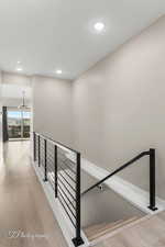 Stairs featuring wood finished floors and recessed lighting