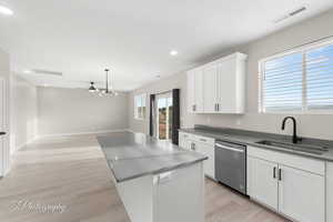 Kitchen featuring dark stone countertops, white cabinets, dishwasher, light wood-style flooring, and recessed lighting