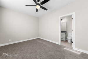 Unfurnished bedroom with carpet floors, ceiling fan, and ensuite bath