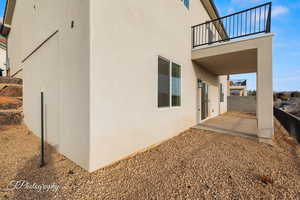 View of side of property featuring a patio, stucco siding, and a balcony