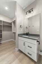 Bathroom featuring a walk in closet, vanity, light wood-style flooring, and recessed lighting