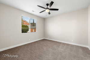 Empty room featuring carpet flooring and a ceiling fan