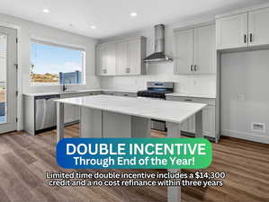 Kitchen featuring light stone countertops, gray cabinets, wall chimney exhaust hood, and recessed lighting