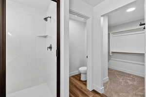 Full bath featuring a spacious closet, a marble finish shower, and light wood-style flooring