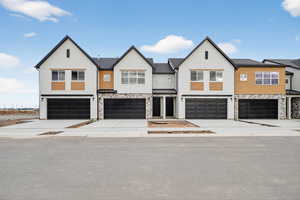 View of front of house featuring stone siding, driveway, a residential view, and a garage