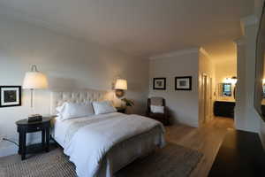 Bedroom featuring ensuite bath, and wood flooring