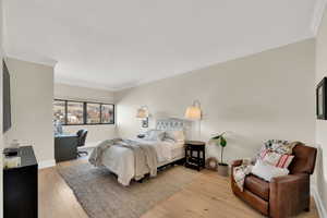 Bedroom with light wood floors and crown molding.