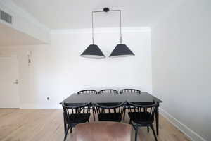 Dining room with light wood floors and crown molding
