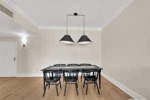 Dining room featuring light wood floors and crown molding.