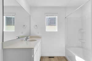 Bathroom with vanity, shower / bath combination, light wood-style floors, and healthy amount of natural light
