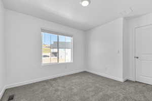 Carpeted spare room featuring baseboards