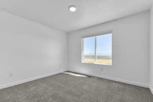 Carpeted spare room featuring baseboards