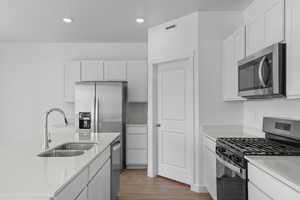 Kitchen with appliances with stainless steel finishes, white cabinetry, wood finished floors, and recessed lighting