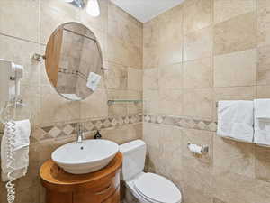 Half bathroom featuring vanity and tile walls