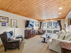 Living area featuring wooden ceiling, carpet flooring, recessed lighting, and crown molding