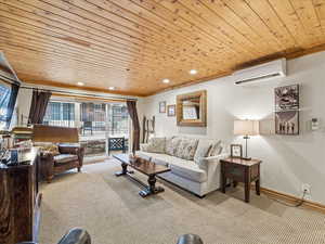 Living room featuring wooden ceiling, recessed lighting, carpet, and a wall unit AC