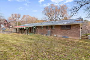 Back of property featuring brick siding, a patio area, and a metal roof