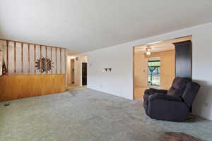 Carpeted living area featuring a ceiling fan