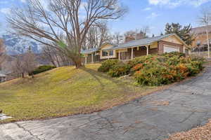 Ranch-style house featuring a front lawn, a chimney, an attached garage, and brick siding