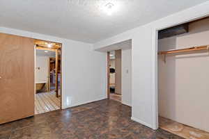 Unfurnished bedroom featuring a textured ceiling and a closet