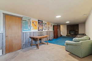 Living area with a textured ceiling, wooden walls, wainscoting, and a brick fireplace