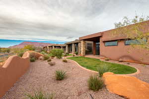 Rear view of house featuring stucco siding, stone siding, and a mountain view