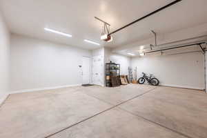 Garage featuring baseboards and a garage door opener