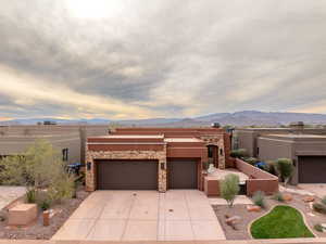 Adobe home with a mountain view, stucco siding, a patio area, concrete driveway, and an attached garage