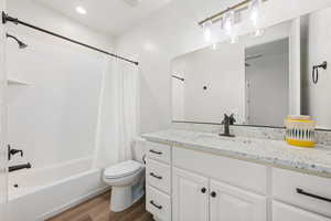 Full bath with vanity, shower / tub combo with curtain, and dark wood-style floors