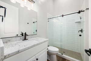 Full bathroom with vanity, a stall shower, and dark wood-style floors