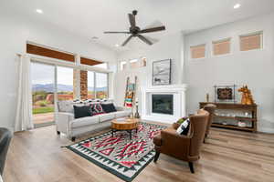 Living area featuring a glass covered fireplace, light wood-style floors, a ceiling fan, recessed lighting, and a mountain view