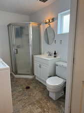 Full bath with vanity, washer / clothes dryer, a shower stall, and a textured ceiling