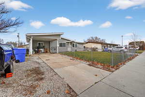 View of front facade featuring driveway, a fenced front yard, and a carport