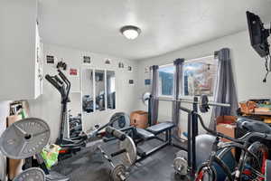 Workout area with a textured ceiling and dark rubber floors