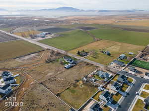 Aerial view of property and surrounding area featuring rural landscape, rows of crops, and a mountain backdrop