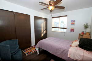 Bedroom featuring multiple closets, dark wood finished floors, and ceiling fan