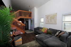 Living area with stairway, a high ceiling, dark wood-style flooring, and healthy amount of natural light