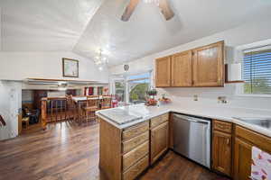 Kitchen featuring a ceiling fan, brown cabinetry, dishwasher, dark wood-style floors, and vaulted ceiling