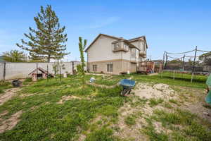 Rear view of house featuring a trampoline and a fenced backyard