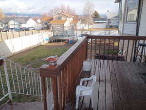 Deck with a fenced backyard, a trampoline, and a residential view