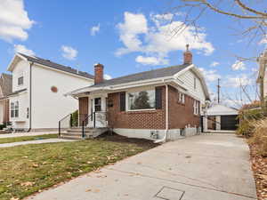 Bungalow featuring brick siding, a chimney, and driveway